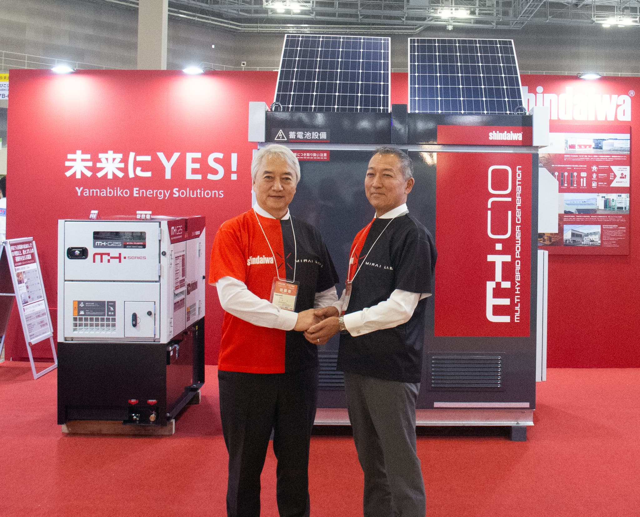 同じユニフォームを着用し握手を交わす両社社長